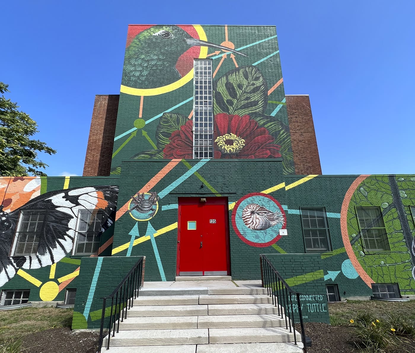 Small green building painted with flowers and wildlife